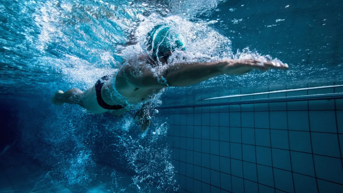 Unterwasseraufnahme einer erwachsenen Schwimmerin beim Kraulen
